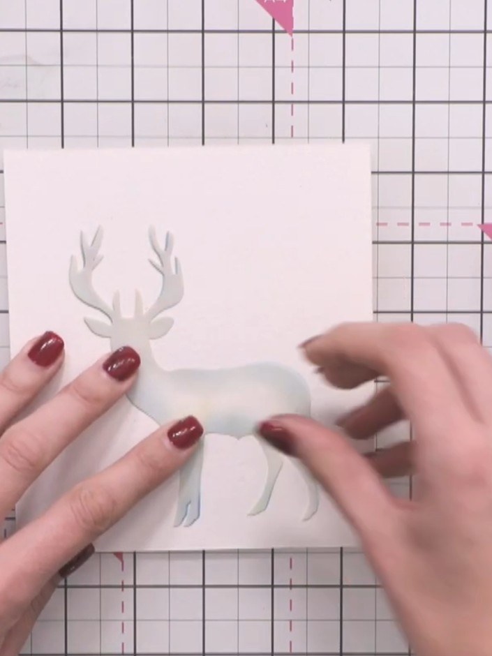 Step 3: Position the interior silhouette stencil of the stag on top of your card panel and secure it in place with a m