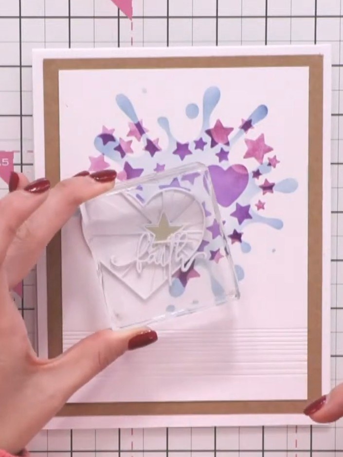 Step 4: Position the layered 'Faith' sentiment on or near the heart element, allowing it to hang slightly off to the s