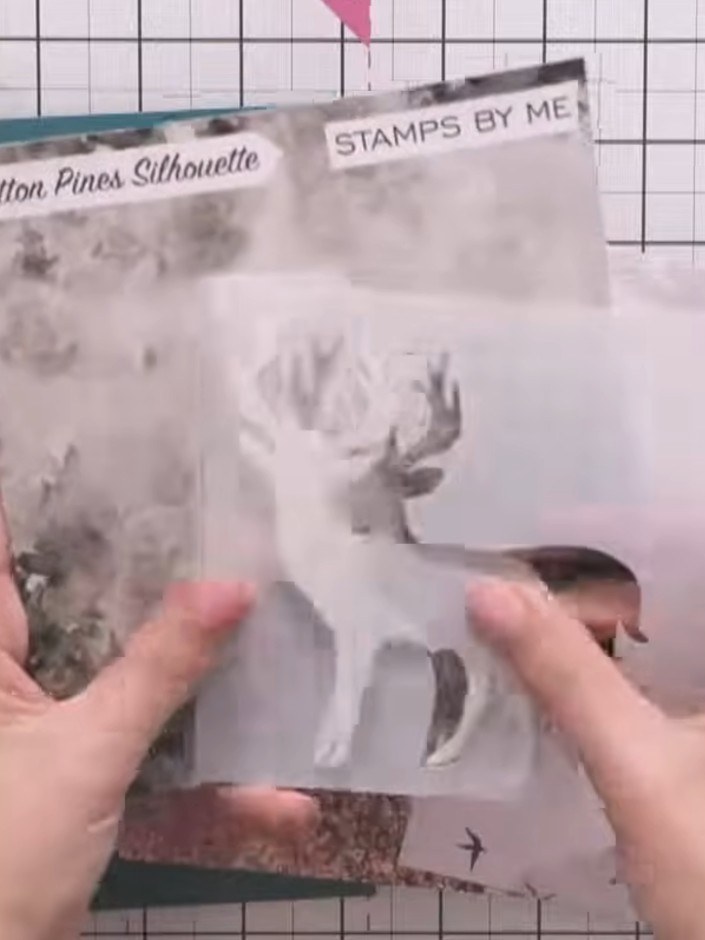 Step 2: Place the Cotton Pines Silhouette stencil mask over the teal card base to protect the stag outline area. Posit