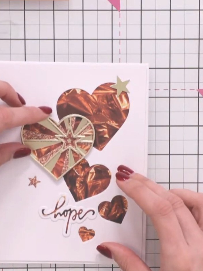 Step 9: Die-cut small star shapes from the paper collection. Position and adhere them as additional embellishments aro