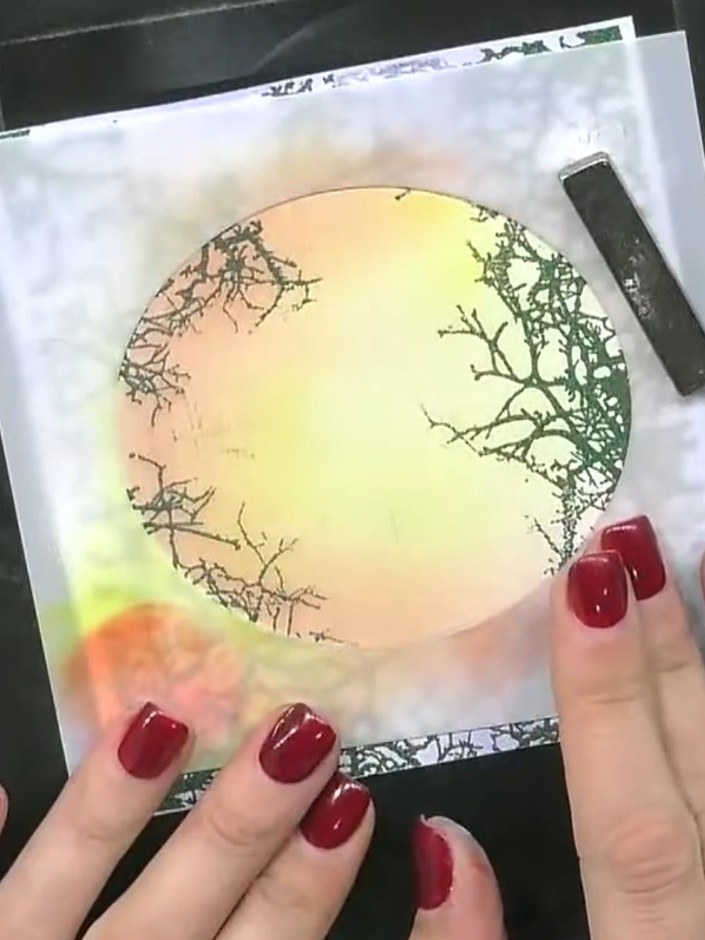 Step 2: Stamp the tree design in black ink within the masked circle area to create a silhouette effect. Remove the mas