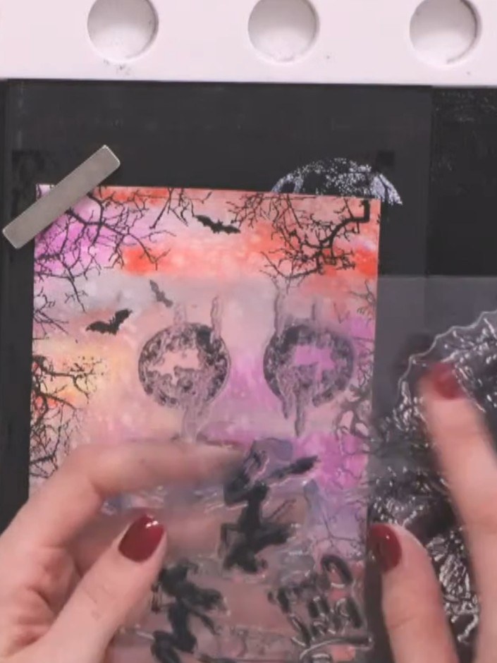 Step 13: Use a circular stencil to add moon shapes in the centre of the card using light grey or black ink. Position th