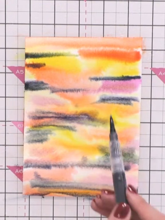 Step 7: Flick clean water onto the watercolour background using a water brush to create texture and the appearance of 