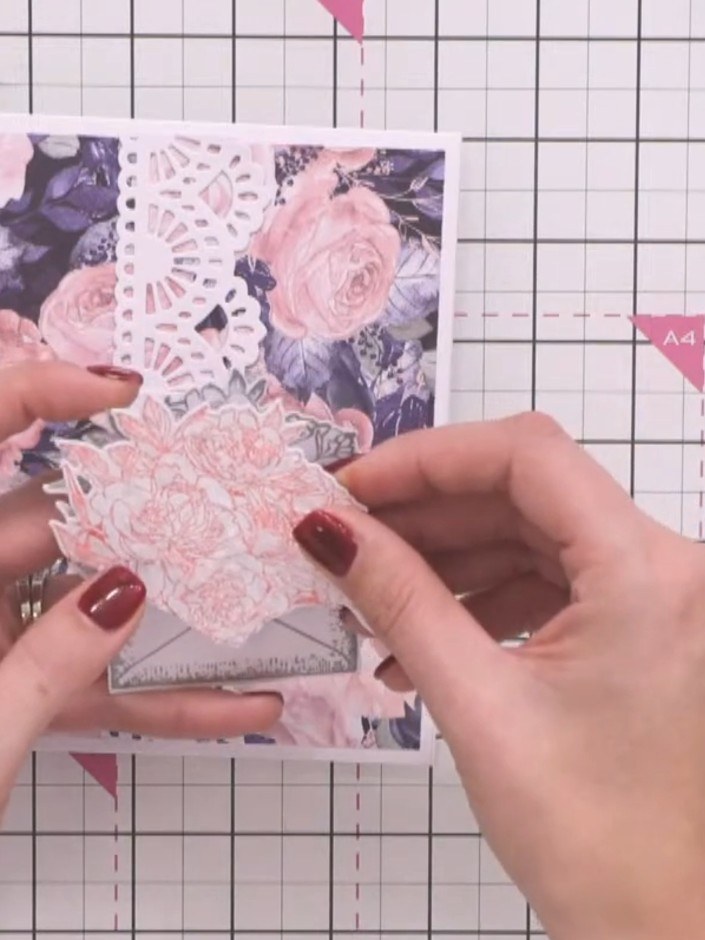 Step 5: Layer the pink flower die-cut on top of the grey envelope stamp to create a 3D bouquet effect. Position the pi