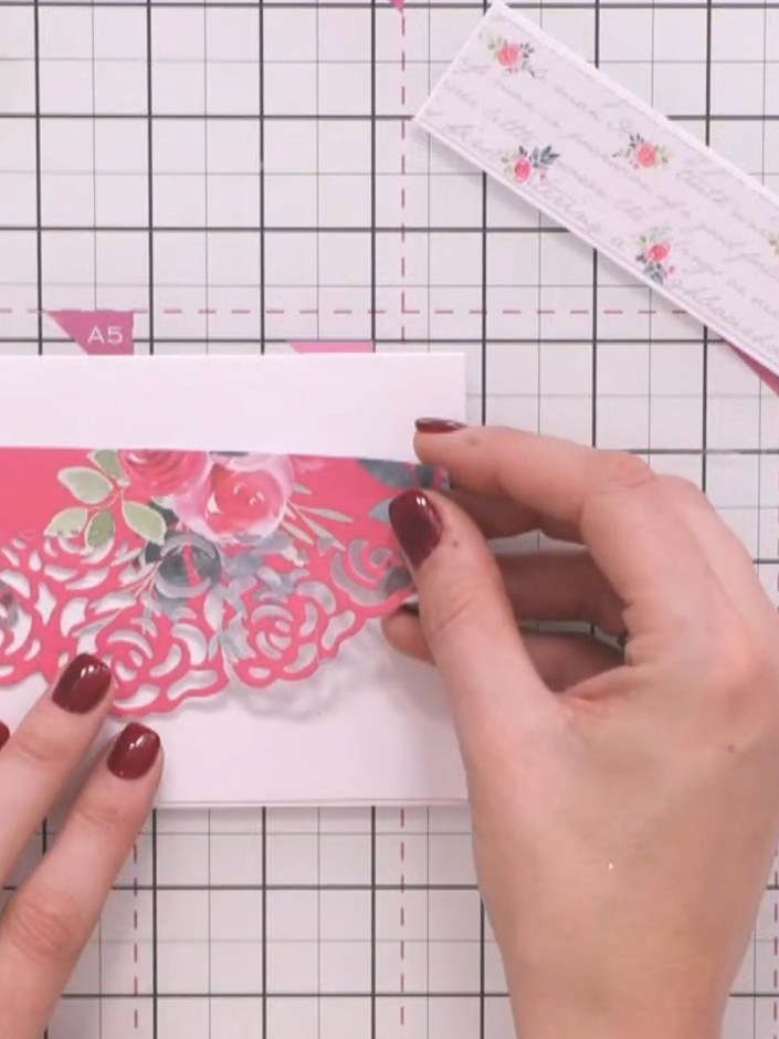 Step 2: Mount the pink die-cut banner strip with floral design onto white cardstock. Smooth it down firmly to ensure g