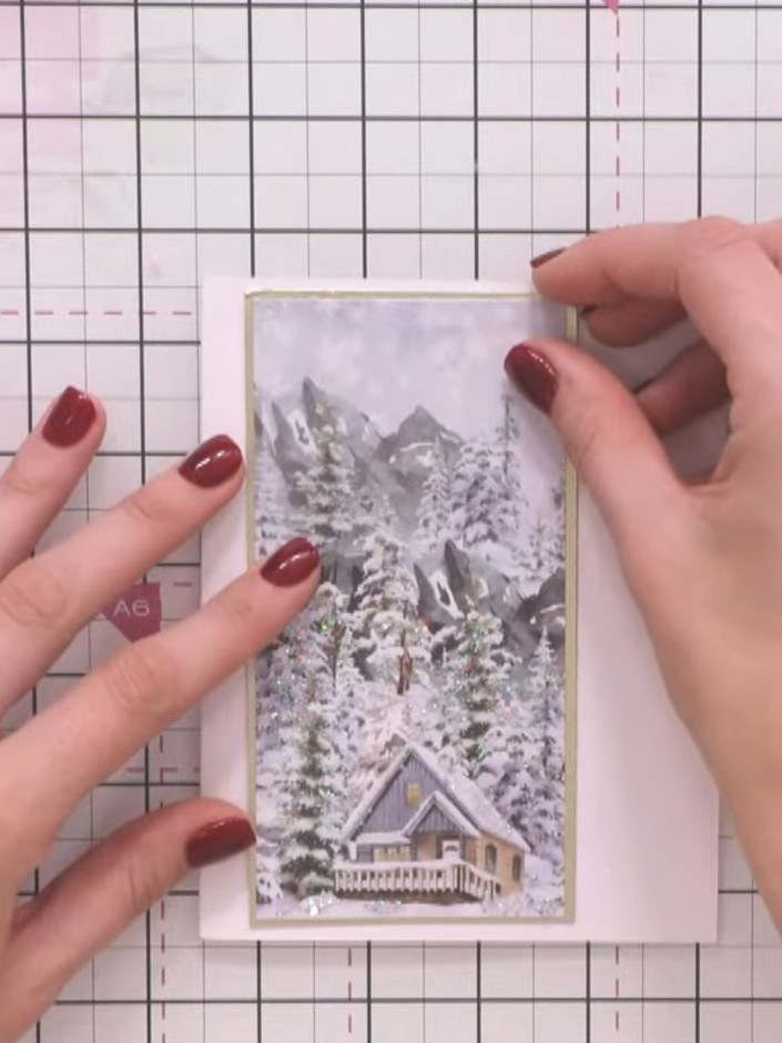 Step 2: Mount the winter scene panel onto gold cardstock to create a backing layer. Position the panel centrally on th