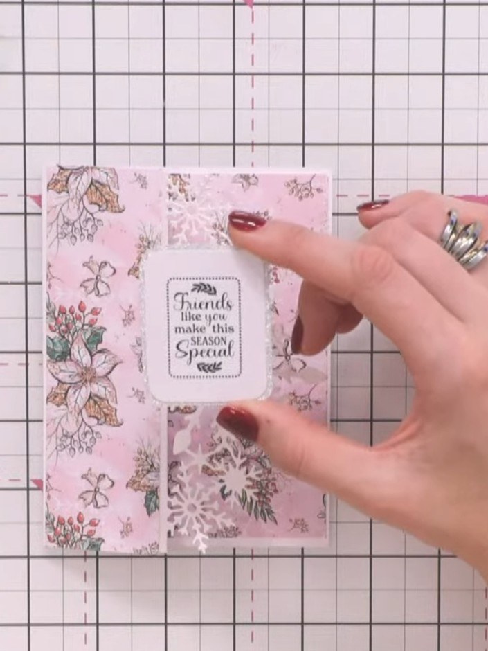 Step 7: Position the sentiment label so it slightly overhangs the top edge of the pink floral panel. Use adhesive to s