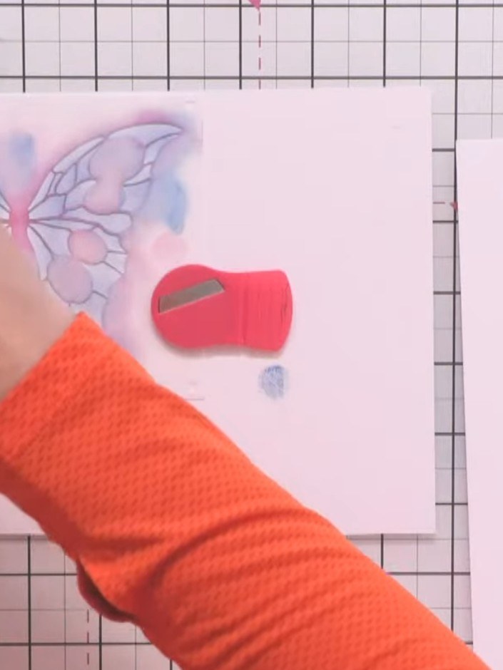 Step 2: Select a teal ink pad and brush colour through the butterfly stencil using a stencil brush, building up the co