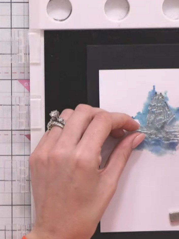 Step 10: Ink the ship outline stamp with black ink and carefully press it onto the watercoloured area of your card to a