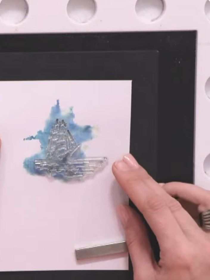 Step 11: Select a sentiment stamp from the set and position it below the ship design on your white card panel to check 