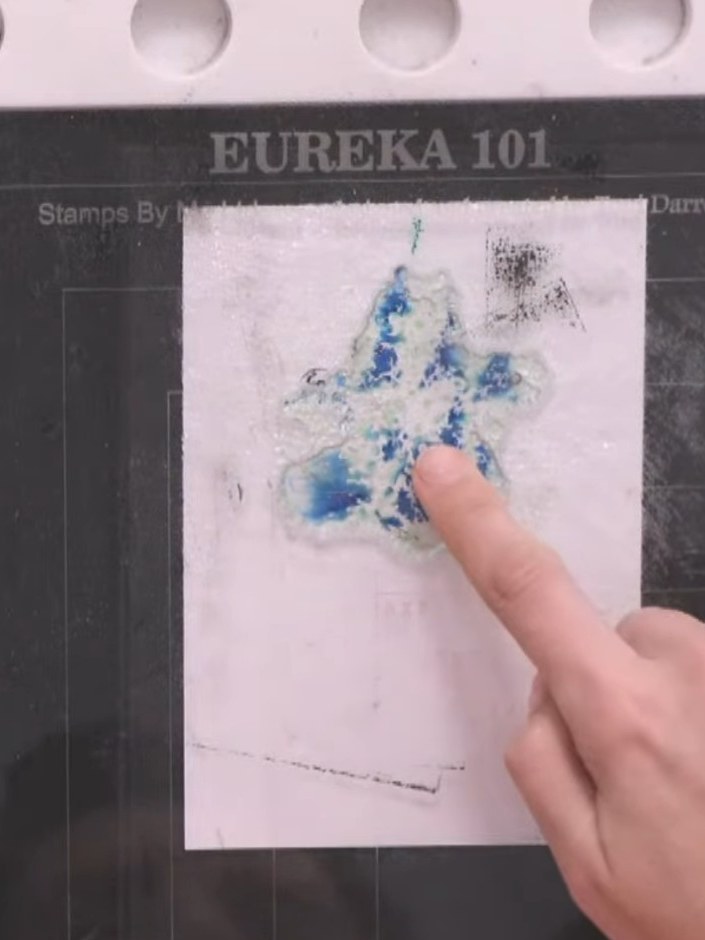 Step 5: Press the stamp firmly onto the white card, holding it in place for a moment to allow the card to absorb the b
