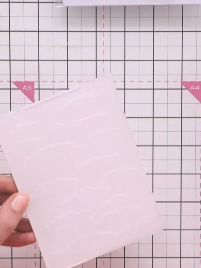 Step 1: Cut a piece of white card stock to fit your embossing folder. Place the card stock into the pink embossing fol