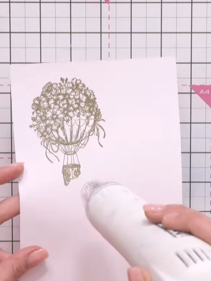Step 10: Apply heat embossing powder to the stamped balloon image using a heat tool, moving it over the design until th