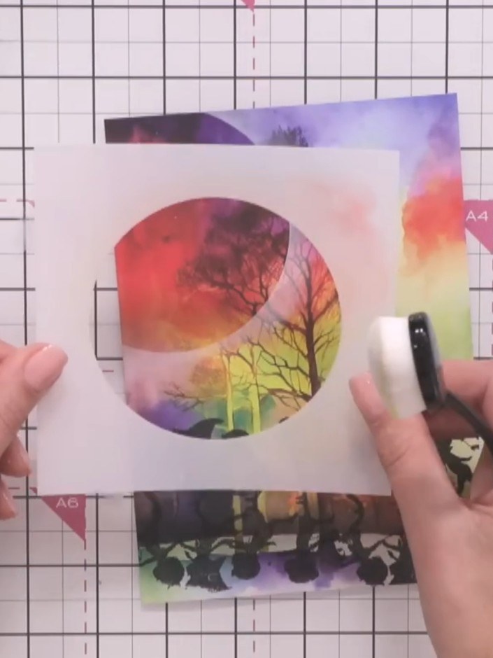 Step 7: Carefully lift away the circular stencil to reveal the glowing moon effect beneath. The rainbow-coloured moon 