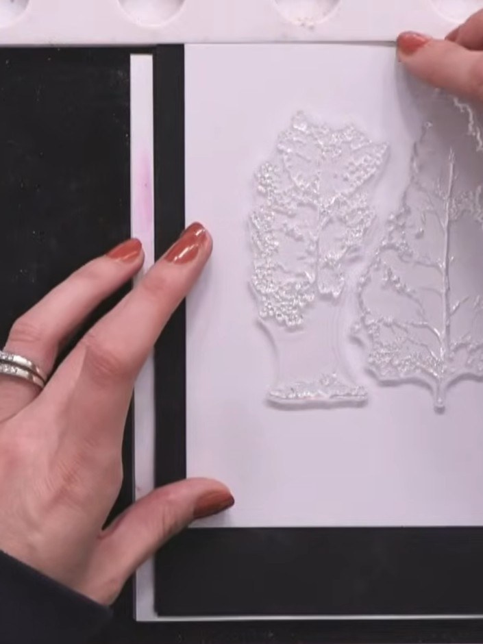 Step 3: Trag pinke Stempelfarbe auf die Blütenköpfe eines Baumstempels auf. Besprüh den Stempel dann mit Wasser, damit die Farben ineinanderfließen.