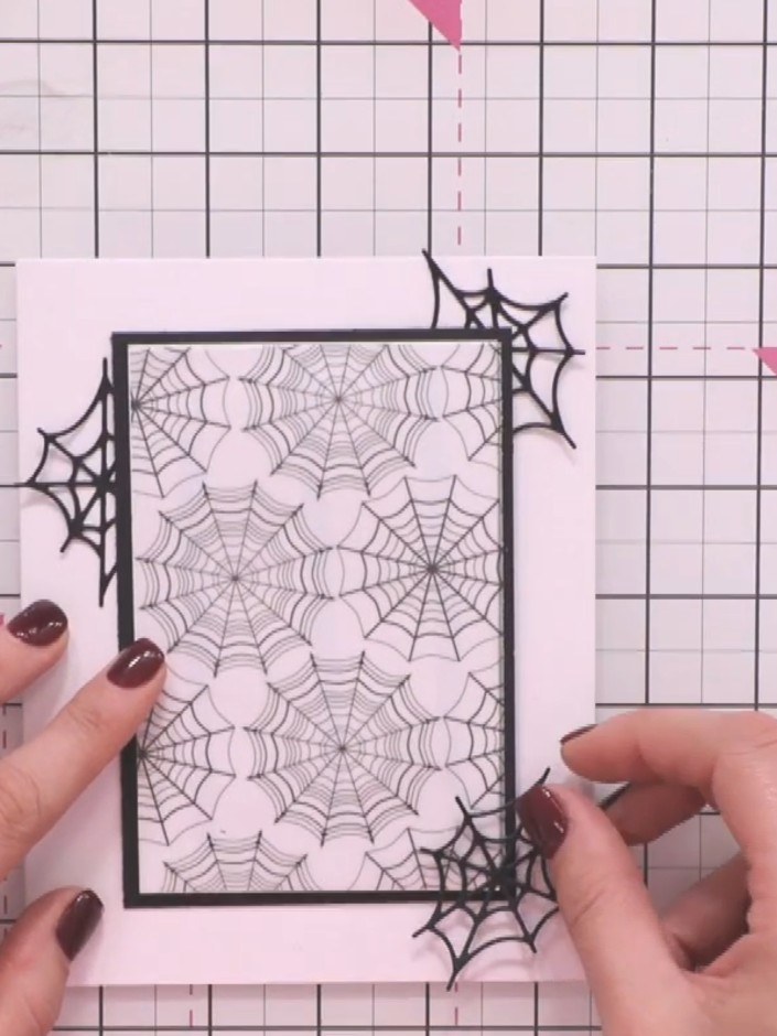 Step 6: Adhere the black spider web frame to the card base, positioning it centrally over the vellum spider web backgr
