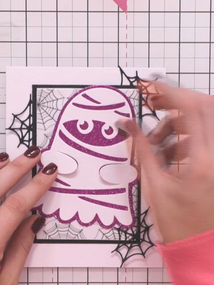 Step 7: Adhere the pink sparkle glitter ghost character to the card front using adhesive, positioning it centrally ove