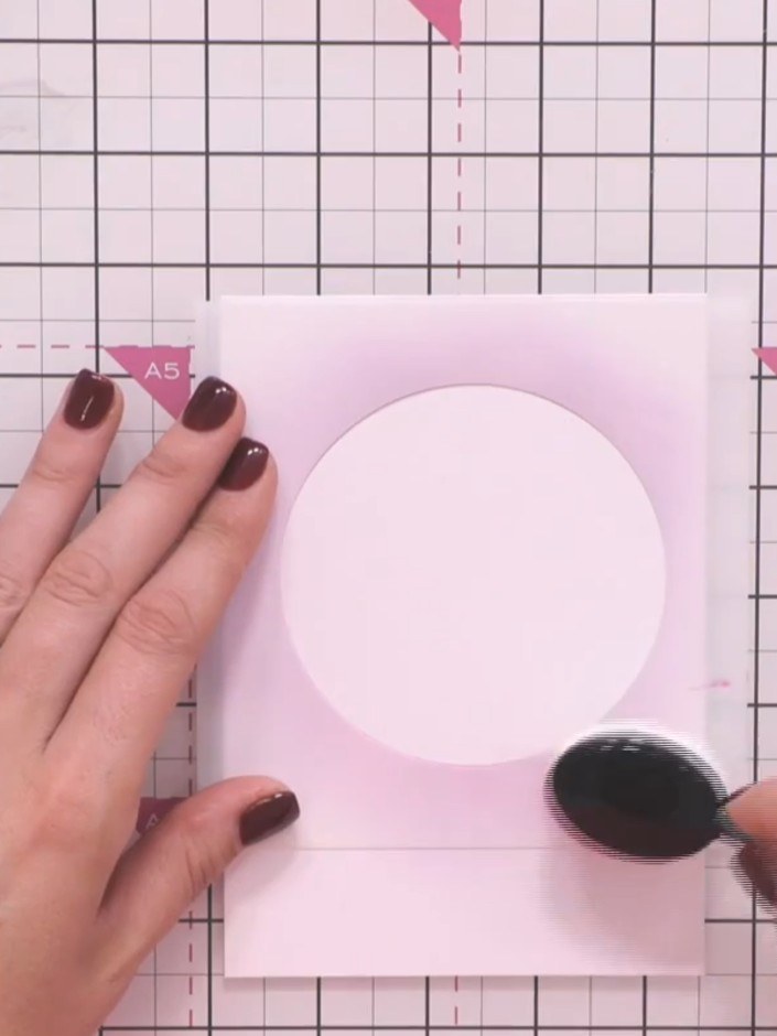 Step 5: Position the exterior stencil piece (the outer frame piece) over the moon area on your pink card panel. Hold i