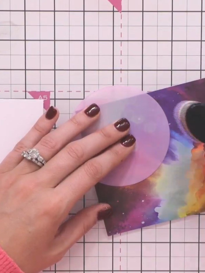 Step 2: Position the circular moon stencil aperture near the top of your galaxy background paper. Hold it in place and