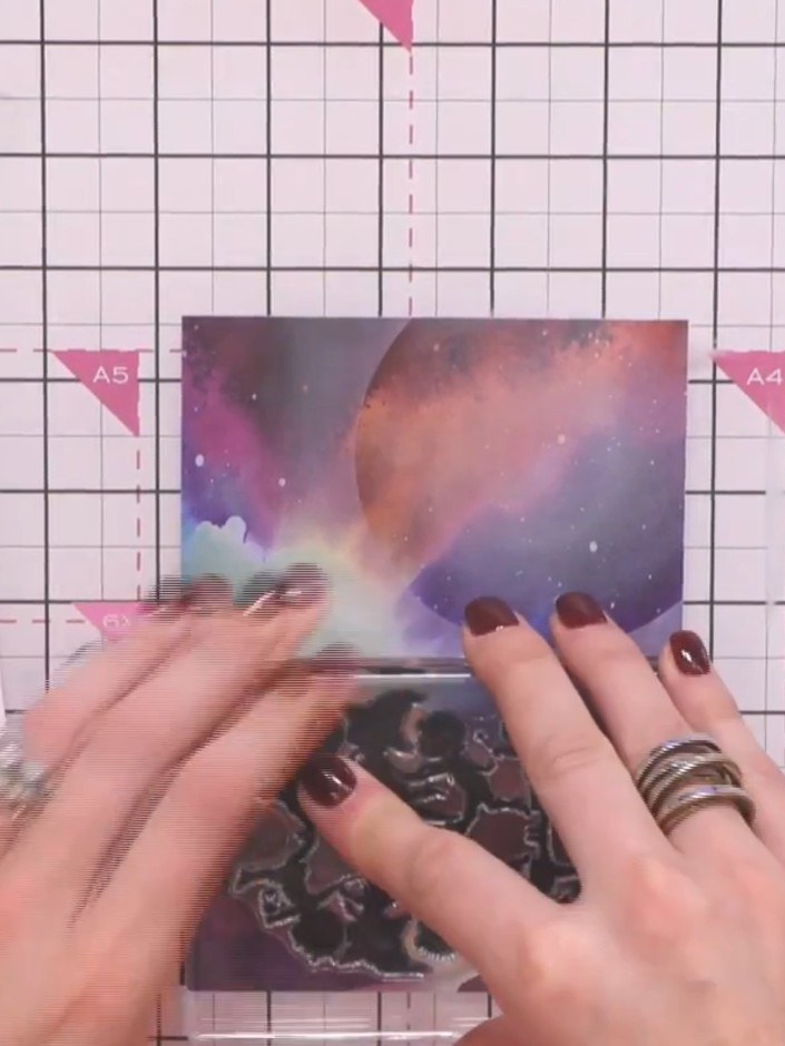 Step 6: Stamp the reflection figures in black ink near the base of the galaxy card where the water or ground area is s