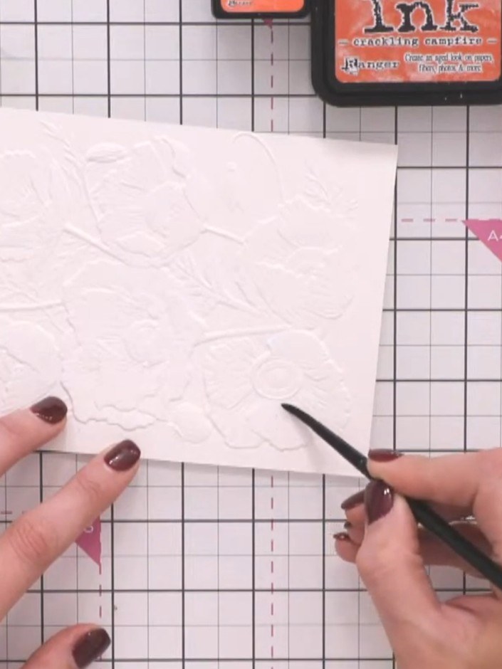 Step 4: Con un pincel limpio y mojado, aplica agua en el primer pétalo del diseño de amapola en relieve de tu tarjeta.