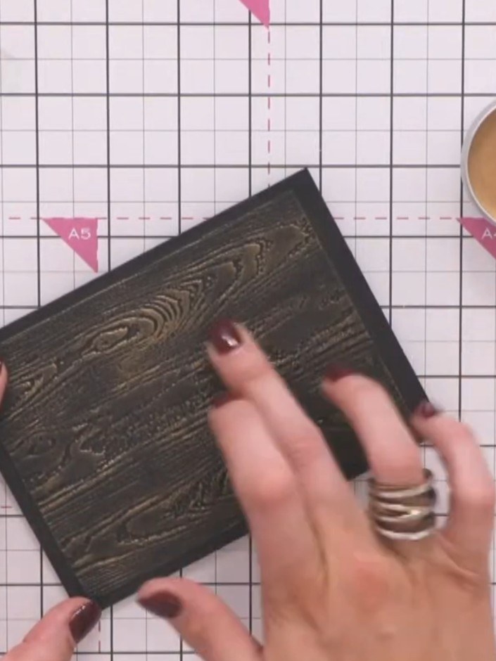 Step 5: Run the Cobbles embossing folder through your die-cutting machine with black cardstock to create a brick-like 