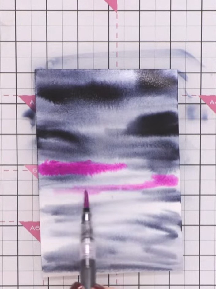 Step 4: Using a fuchsia pink watercolour brush pen, add colour to the middle section of your wet paper, creating horiz