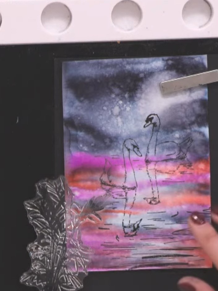 Step 4: Stamp the foliage elements in black ink along the top edge of the card, positioning them to frame the swan ima