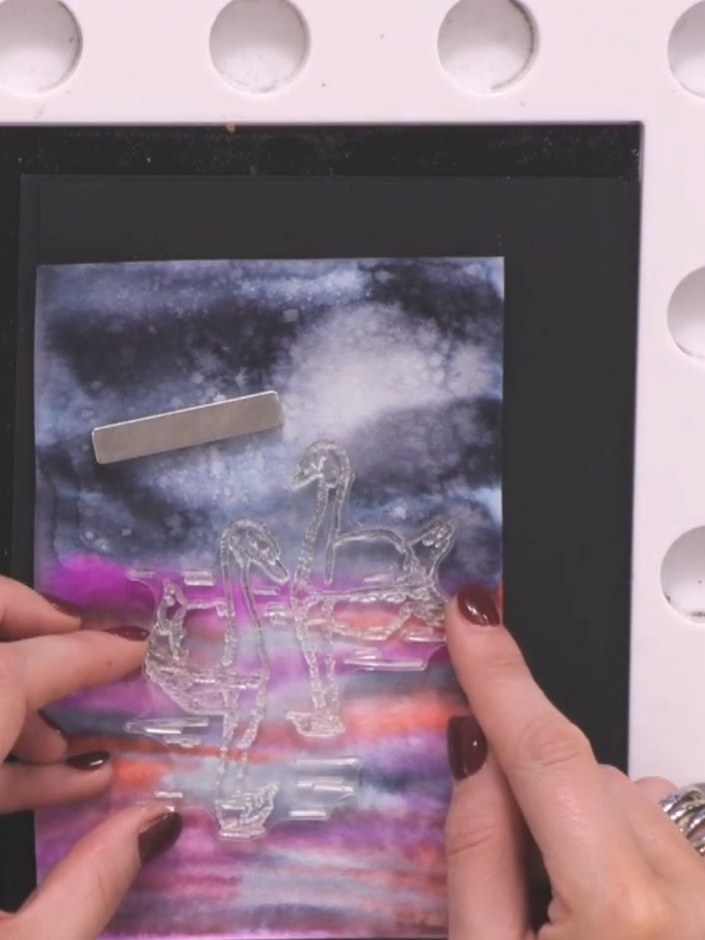 Step 10: Stamp the swans and foliage from the reflection stamp set in black ink onto the dry card, positioning them wit