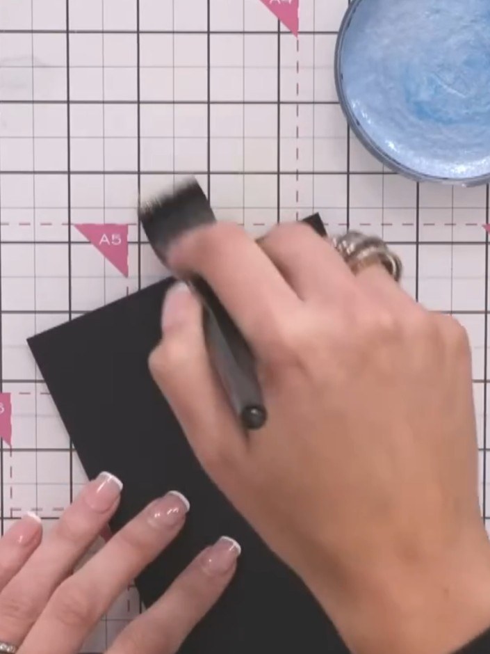 Step 2: Use a brush to swipe the activated metallic inks across the black cardstock in downward strokes, layering the 