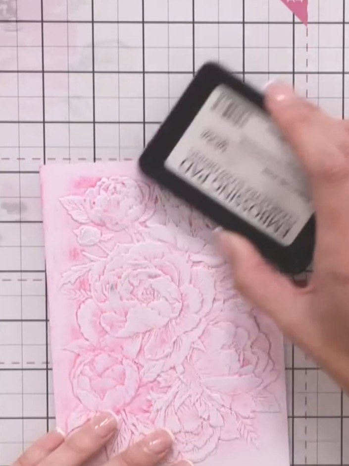Step 9: Apply sticky ink to the embossed floral design on the pink card. Sprinkle gold embossing powder over the inked
