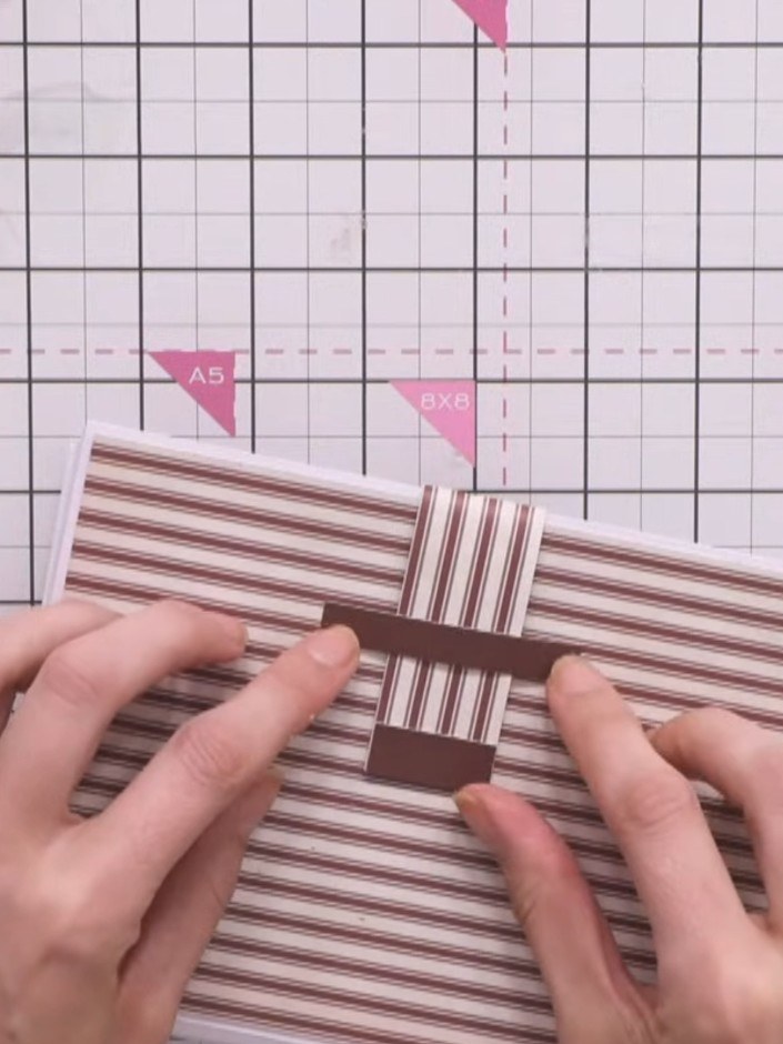 Step 9: Glue the brown striped closure wrap around the back of the album, positioning it so the decorative tip can tuc
