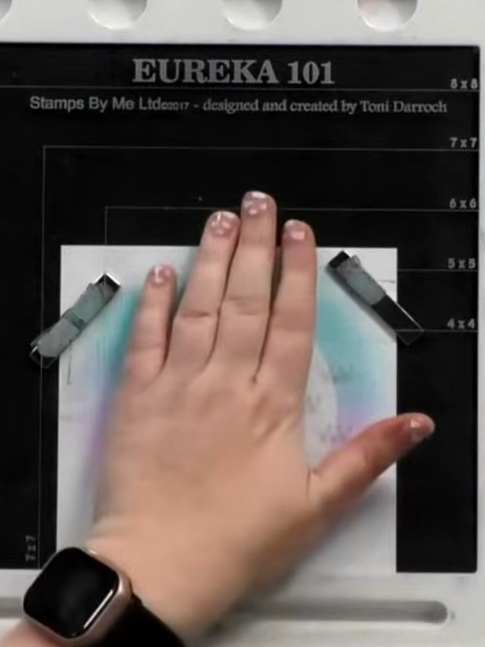 Step 2: Position the reflection dancer stamp in the centre of the blended background panel. Use your hand to hold it f