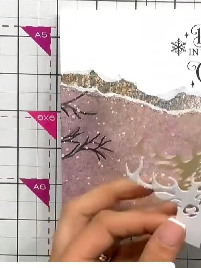 Step 9: Optionally add white embossed decorative elements or sparkle to the stag's antlers for extra embellishment. Th