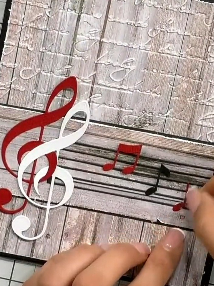 Step 6: Position and adhere the treble clef die cuts as the focal point of your card. Layer the red, white, and gold t