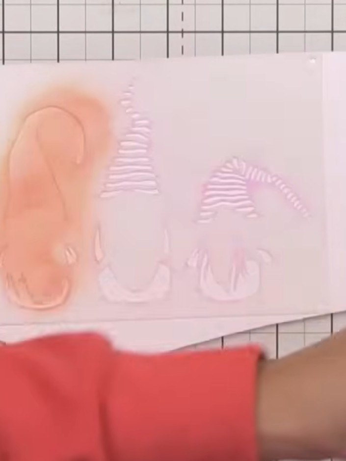 Step 4: Using a separate brush, apply red ink to a second gnome's hat. Then use another clean brush to add green or te
