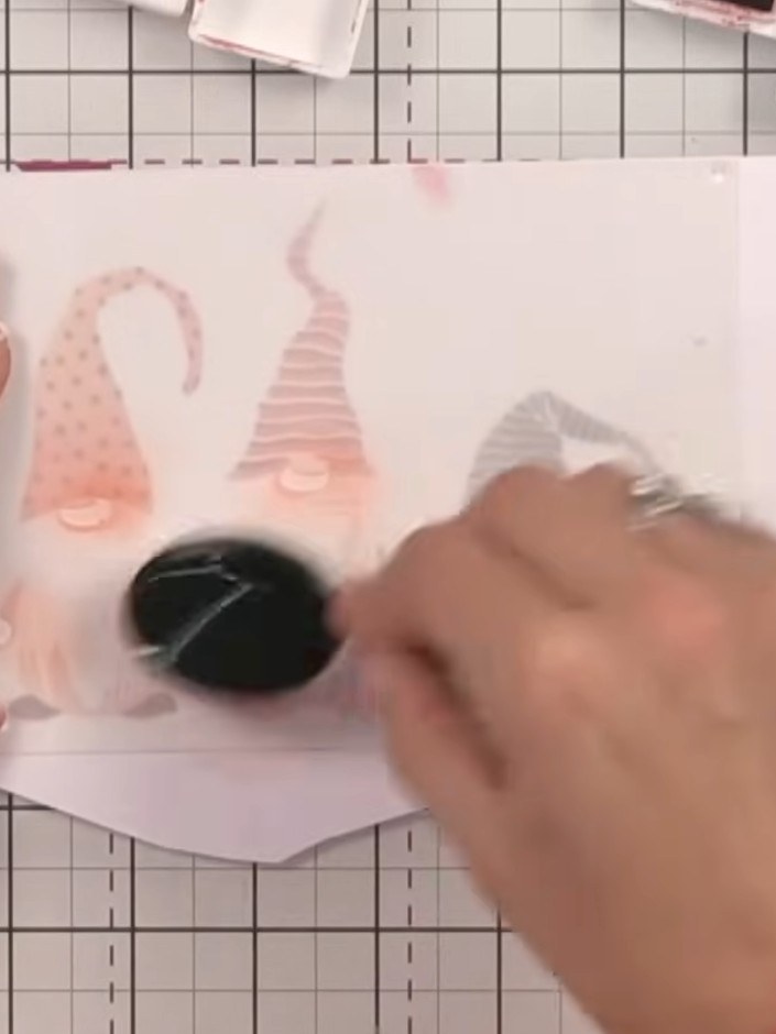Step 9: Stamp the gnome design onto the stencilled layers using black ink. Press the stamp firmly to ensure a clear im