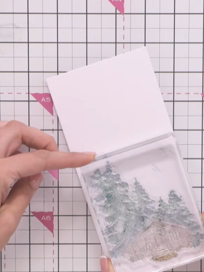 Step 4: Press the cabin stamp firmly into the wet sprayed card to allow the ink to bleed and create a watercolour effe
