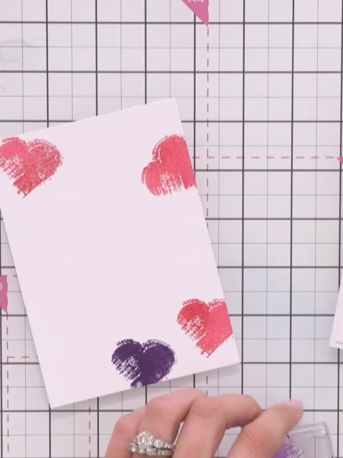 Step 3: Clean the stamp and ink it in purple. Stamp three more hearts in different areas of the card to create a varie