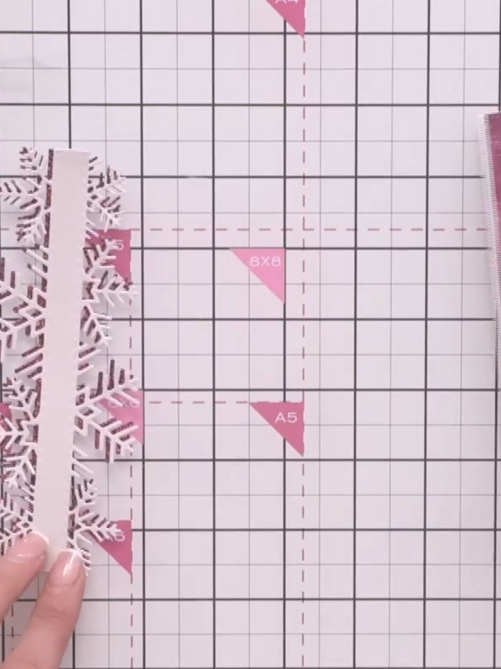 Step 6: Die-cut the snowflake border strip from white cardstock. Position and adhere it horizontally across the centre