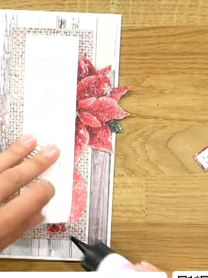Step 6: Apply glue to the back of the pink poinsettia embellishment and position it on the right side of the card, ove