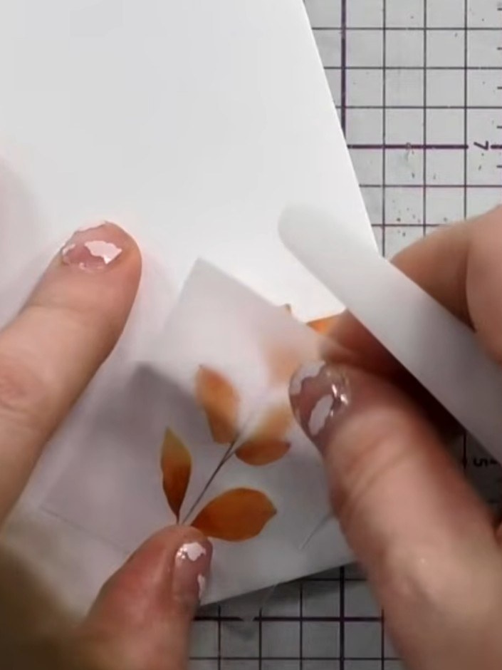Step 6: Carefully peel away the rubon backing sheet from the vellum to reveal the transferred orange leaf design on yo