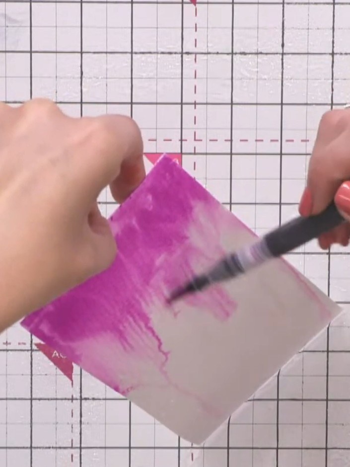 Step 5: Whilst the card is still damp, use a brush to tap splats of pink colour onto the wet surface to create additio