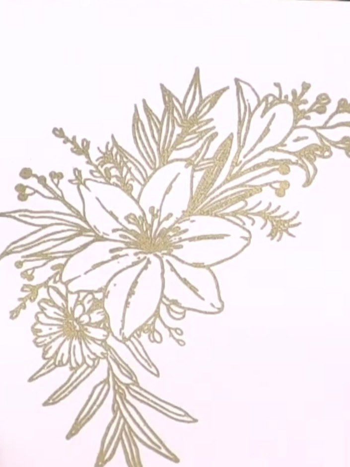 Step 11: Adhere the gold embossed floral element to the front of the card using foam pads, positioning it slightly off-