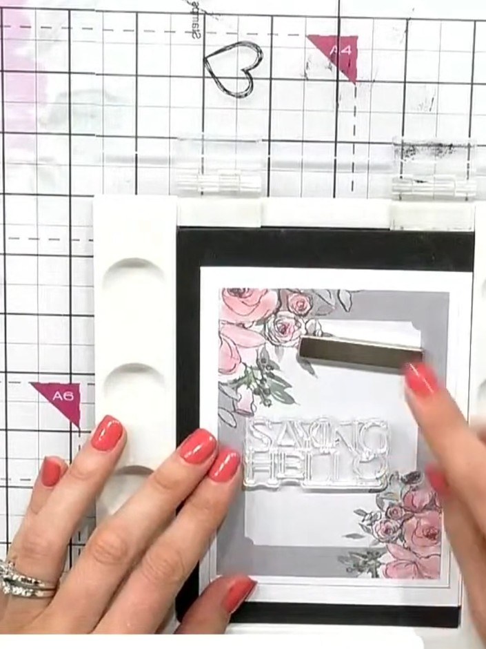 Step 2: Stamp a sentiment such as 'Saying Hello' onto the card front using black ink, positioning it at a jaunty angle