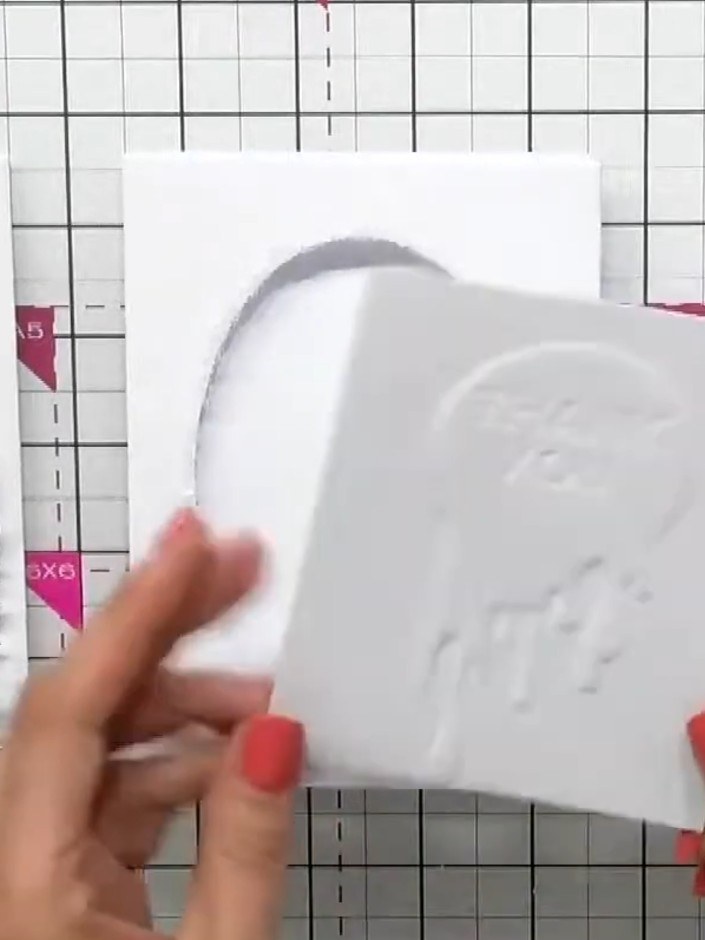 Step 6: Layer the padded flower elements on top of the aperture window card to create dimension. Position the fussy-cu