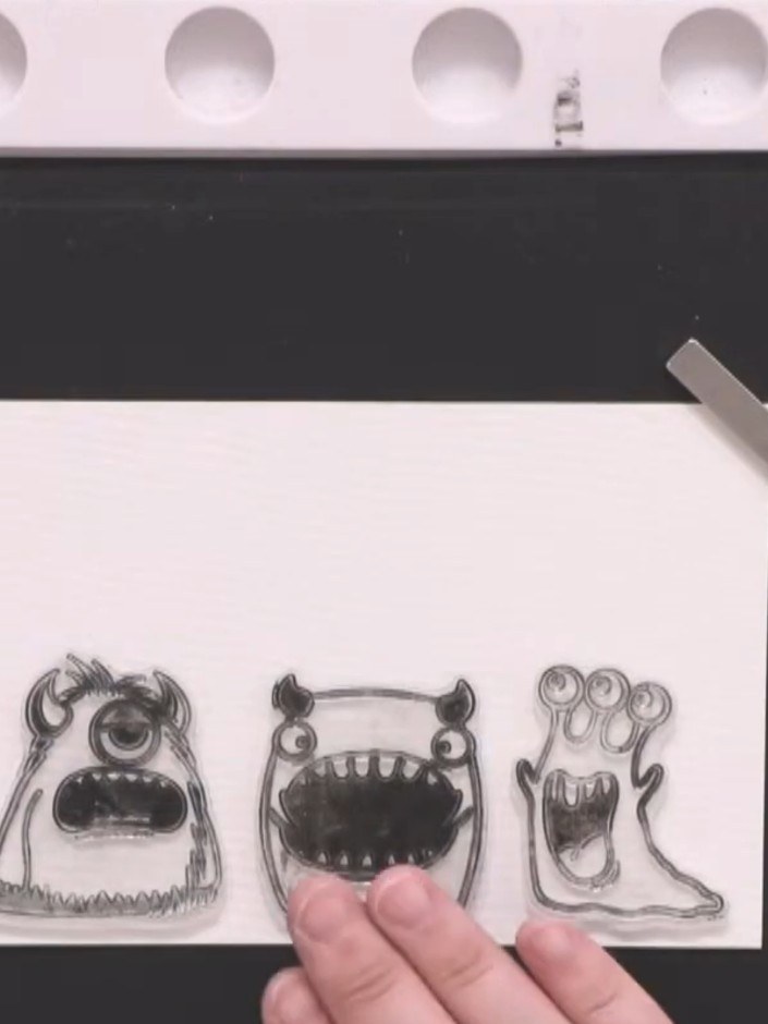 Step 2: Select your monster stamp designs from the set. Position them on the white card panel, placing the larger char