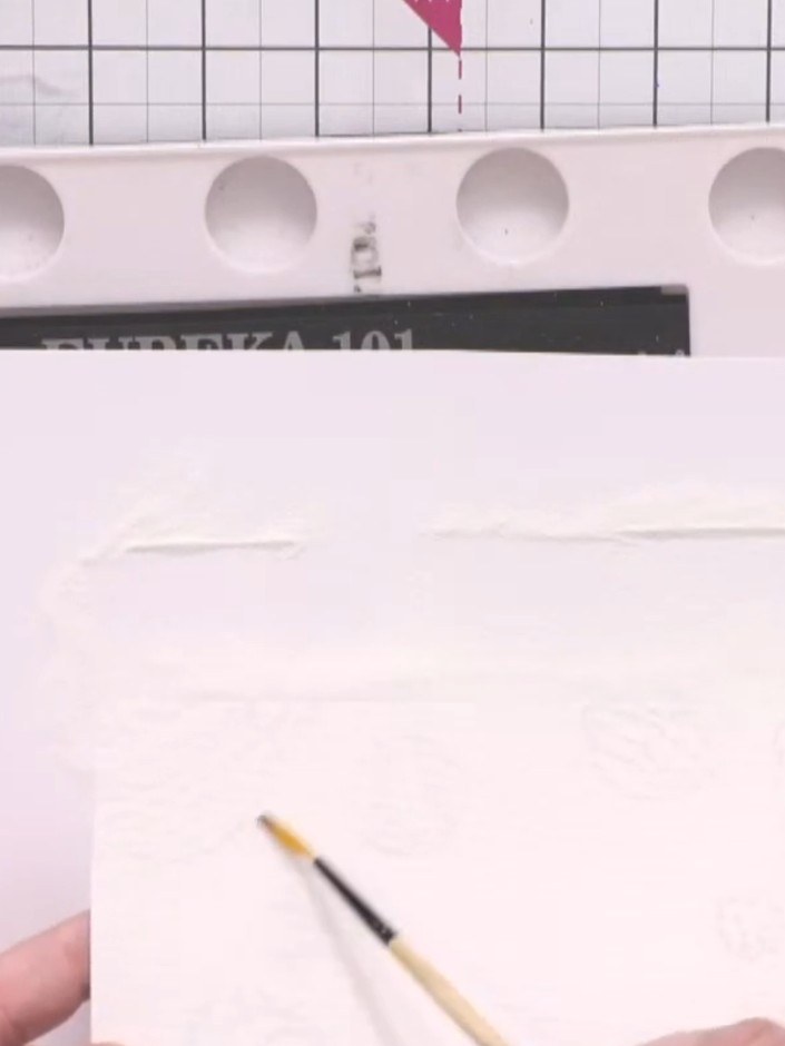 Step 8: Using a clean water brush, wet the card around the embossed planets and monsters, being careful to leave the e