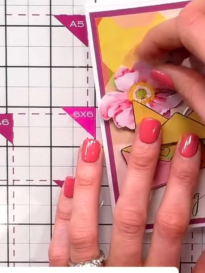 Step 7: Build a small bouquet by layering the die-cut flowers and foliage elements into the heart aperture. Tuck the s