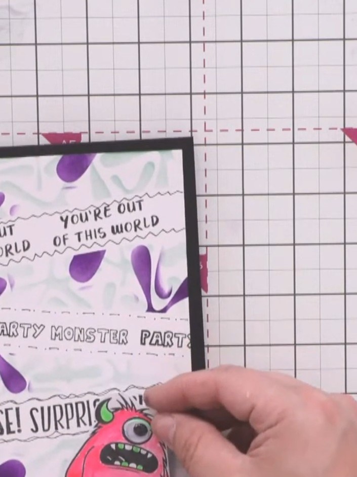 Step 11: Mount the pink monster character onto the card front using foam pads, positioning it at an angle in the lower 